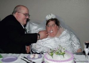 Толстый жених кормит с ложечки очень толстую невесту за свадебным столом.  Прикольные фото со свадьбы.
