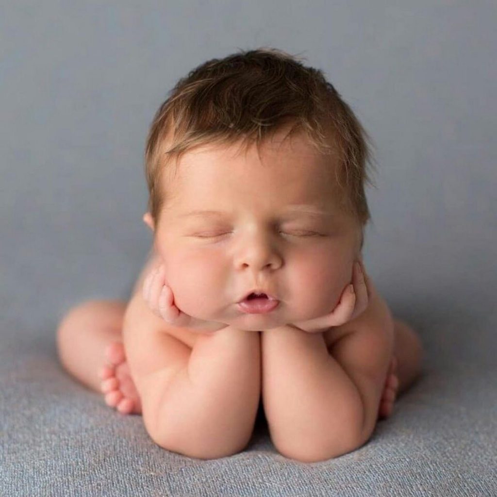 Маленький мальчик лежит с закрытыми глазами оперевшись на локти.