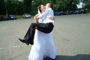 Невеста держит на руках жениха. Пара целуется.  Прикольные фото со свадьбы.