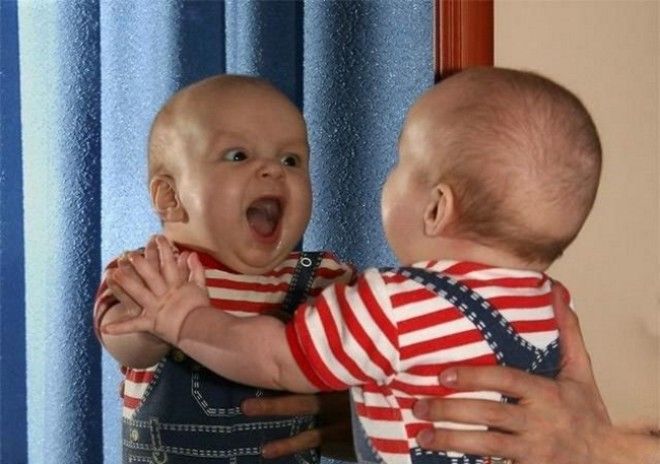 Смешной маленький мальчик в футболке в красную полоску кричит на своё отрожение.