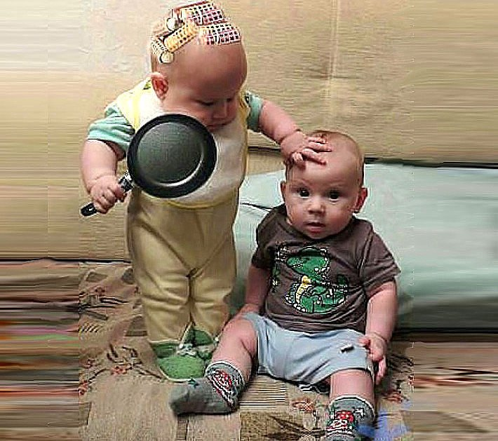 Лысая девочка в бигудях держит в одной руке сковороду, а другую руку положила на голову сидящему маленькому мальчику.