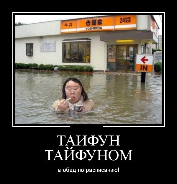 Азиатка стоит по шею в воде в затопленном городе и ест лапшу палочками.