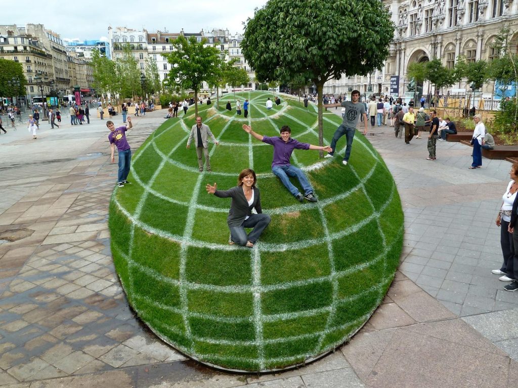 Люди сидят на газоне в виде глобуса. Иллюзия.
